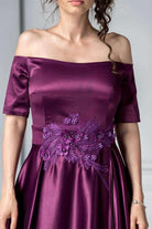 Abito lungo svasato viola scuro lucido Artista con ricami floreali e scollatura a barchetta, tessuto elegante e raffinato.