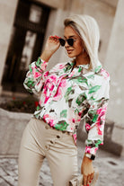 Camicia bianca a fantasia floreale Moda-Mania con bottoni, maniche lunghe e dettaglio di bottoni decorativi.