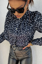 Camicia nera Moda-Mania con pois bianchi, rouches e bottoni dorati, dettaglio del tessuto e design elegante.