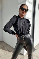 Camicia nera in viscosa Moda-Mania con collo alto, dettagli rouches e bottoni dorati, vista frontale su sfondo neutro.