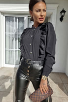 Camicia nera in viscosa Moda-Mania con collo alto, dettagli rouches e bottoni dorati, visibile davanti su modella.
