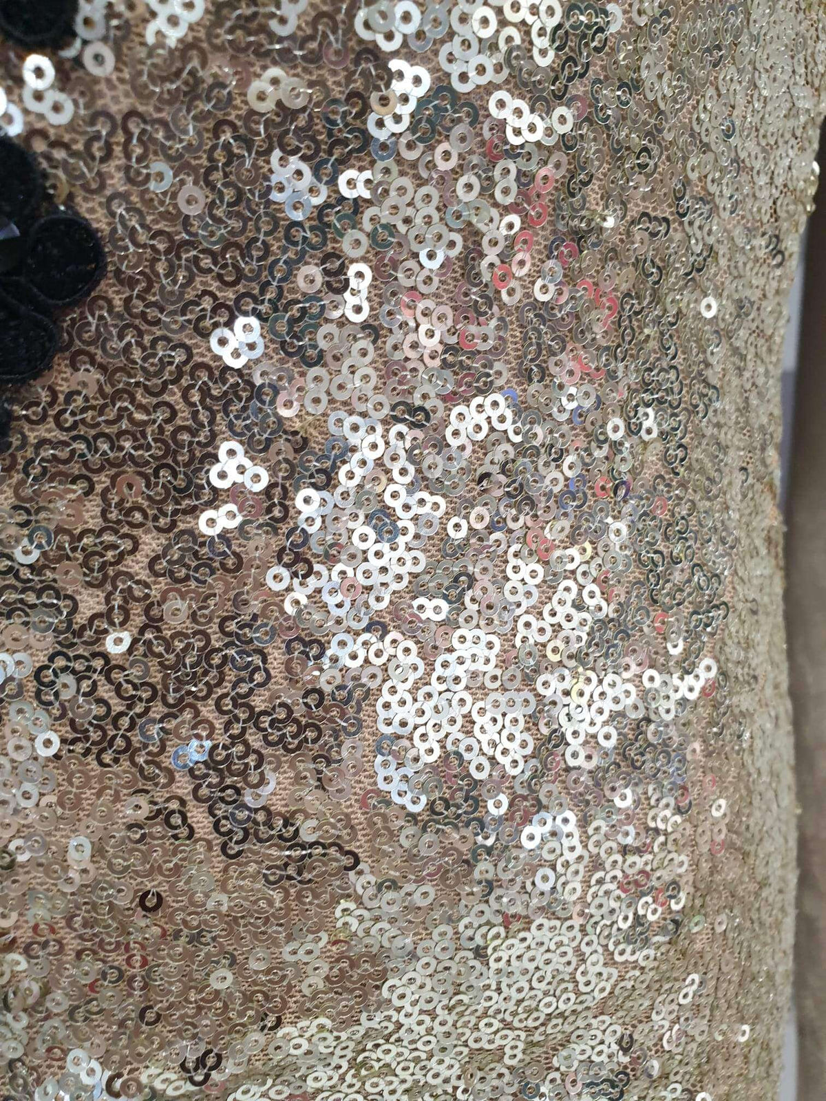 Abito lungo a sirena dorato Chanttal in paillettes con spacco centrale e ricami neri, visibile in primo piano.