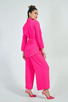 Completo curvy fucsia fluo Moda-Mania con giacca doppiopetto e pantaloni a gamba larga, accessoriato con cintura.