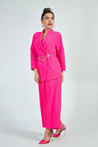 Completo curvy fucsia fluo di Moda-Mania con giacca doppiopetto e pantaloni a gamba larga, accessoriato con cintura.