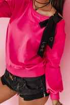Maglia fucsia in cotone con maniche lunghe e fiocco nero decorativo su una spalla, stile denim e sportivo, Moda-Mania.