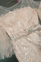 Abito midi aderente beige in pizzo Moda-Mania con maniche a campana in tulle e cintura inclusa, vestibilità elegante e femminile.