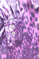 Camicia elegante Moda-Mania a fantasia leopardata viola con maniche a sbuffo e bottoni gioiello, dettaglio visibile in primo piano.