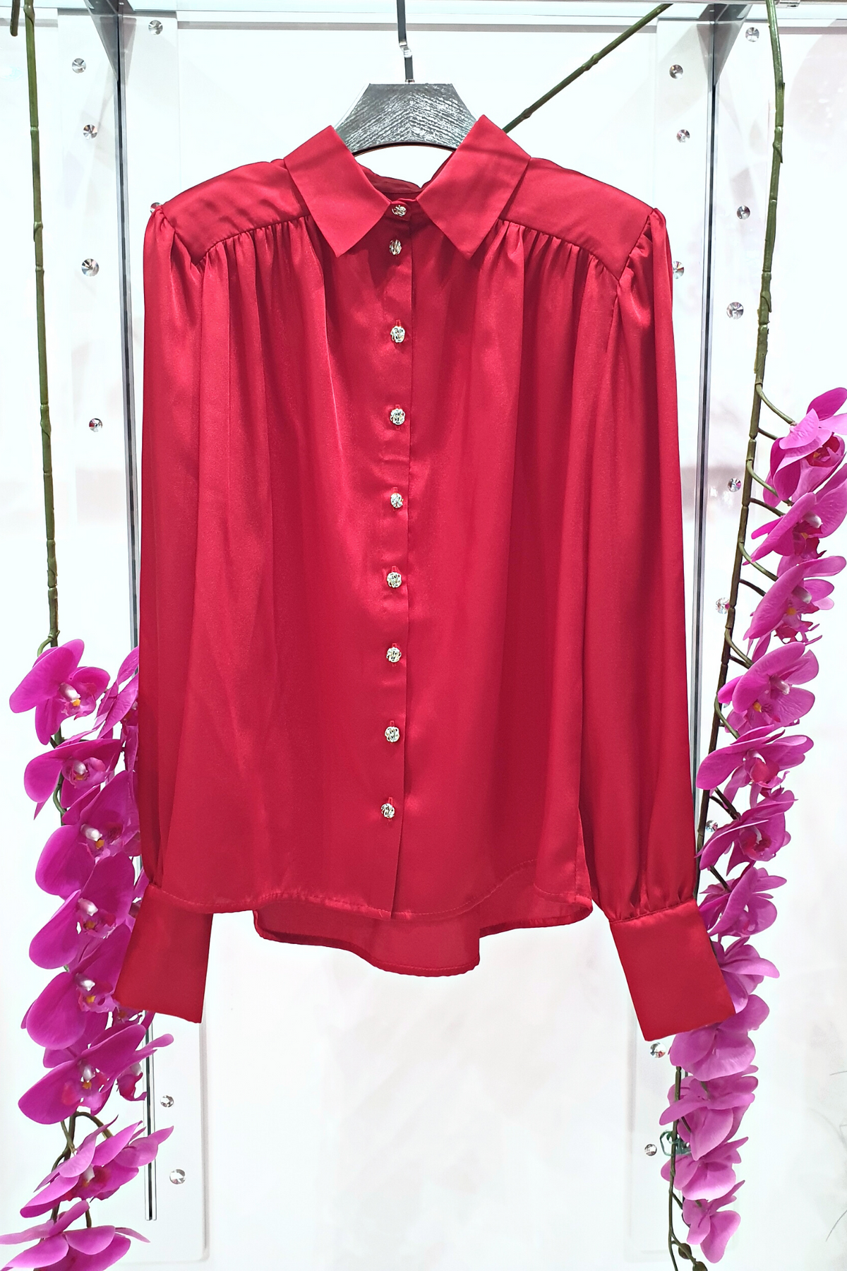 Camicia elegante rossa Moda-Mania in satinato con maniche a sbuffo e bottoni gioiello bianchi, dettaglio tessuto e design raffinato.