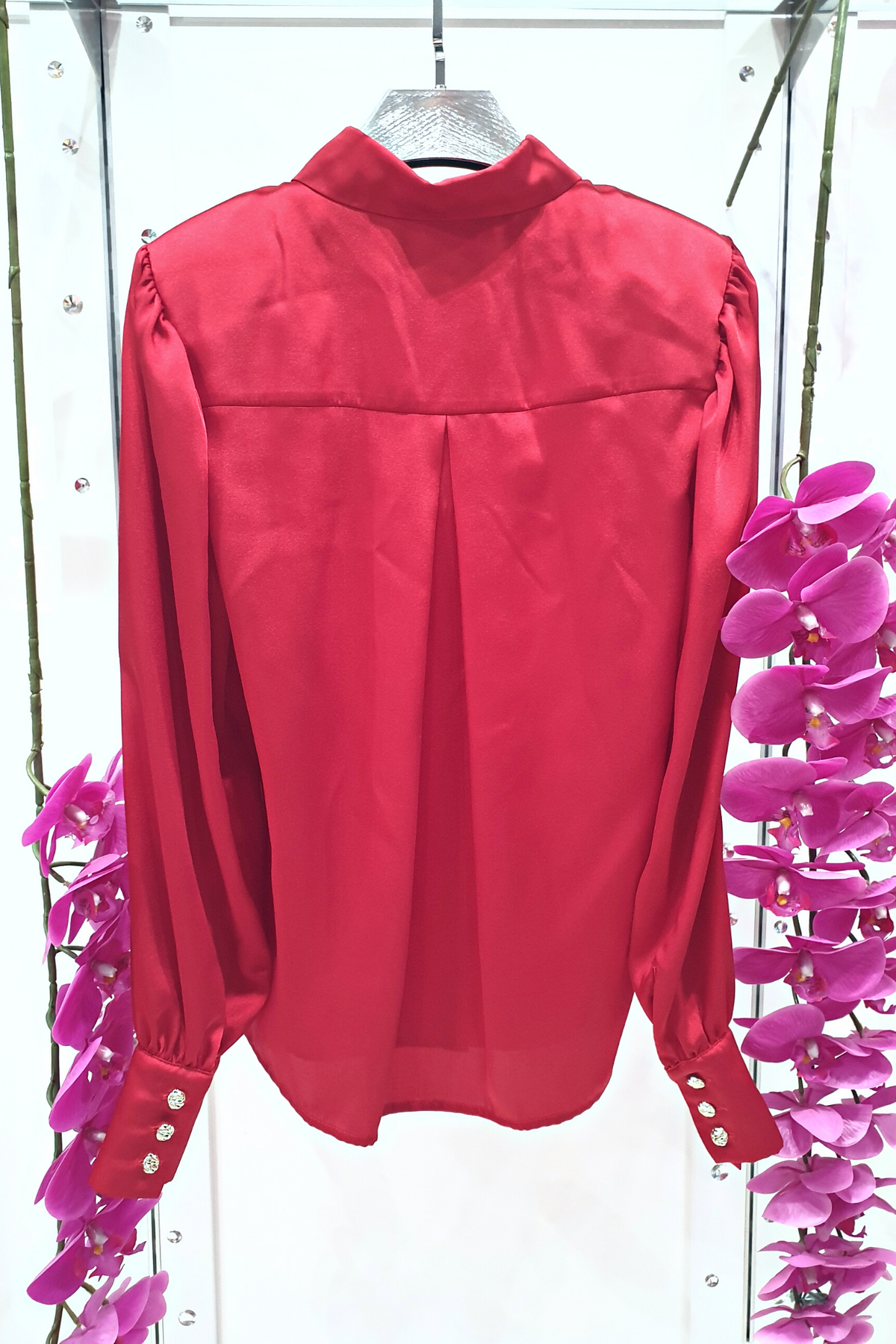 Camicia elegante rossa Moda-Mania in tessuto satinato con maniche a sbuffo e bottoni gioiello bianchi, dettagli raffinati.