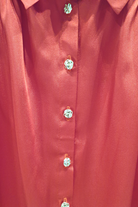 Camicia elegante rossa Moda-Mania in tessuto satinato con maniche a sbuffo e bottoni gioiello bianchi, vista frontale.