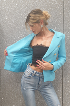 Giacca da tailleur doppiopetto azzurro Moda-Mania, foderata internamente, con bottoni decorativi dorati e dettagli eleganti.