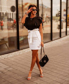 Gonna corta bianca in denim Moda Mania, vita alta con balza e cintura allacciabile, dettaglio di moda e stile casual.
