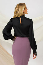 Blusa elegante nera Pretty Girl con collo e polsini rifiniti in pizzo, tessuto leggero e dettagli raffinati, vista frontale.