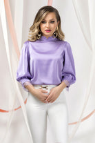 Blusa lilla Pretty Girl con collo alto e polsini rifiniti in pizzo, tessuto leggero e dettagli eleganti, stile femminile e raffinato.